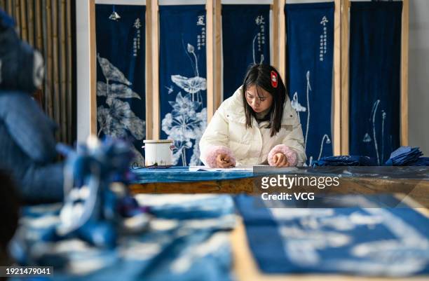 Craftswoman draws batik patterns on cloth to make a batik painting ordered for the upcoming Chinese Spring Festival at a workshop on January 10, 2024...