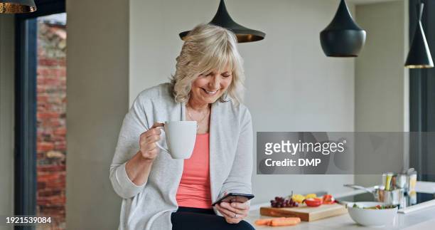 woman, drinking coffee and smartphone or senior in kitchen, funny online conversation and social media. happy mature person, cellphone and internet connection or mobile app for communication at home - food and drink icon stock pictures, royalty-free photos & images