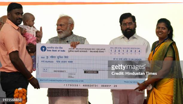 Prime Minister Narendra Modi hands over the cheque to welfare shcme beneficiaries and people affected by development projects during inauguration and...