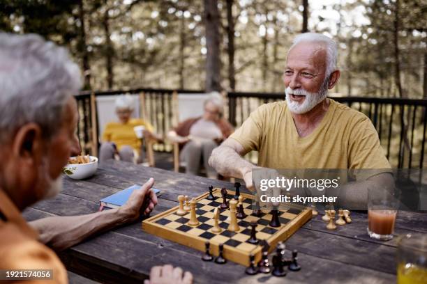ältere männer spielen schach während des frühlingstages auf einer terrasse. - schach stock-fotos und bilder