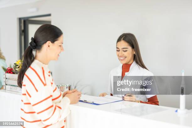 patient signing documents in dental clinic - arztpraxis empfang stock-fotos und bilder