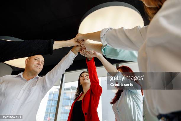 unified vision: business colleagues joining hands in unity, fostering team spirit in a creative luxury office setting - turkey coup photos et images de collection