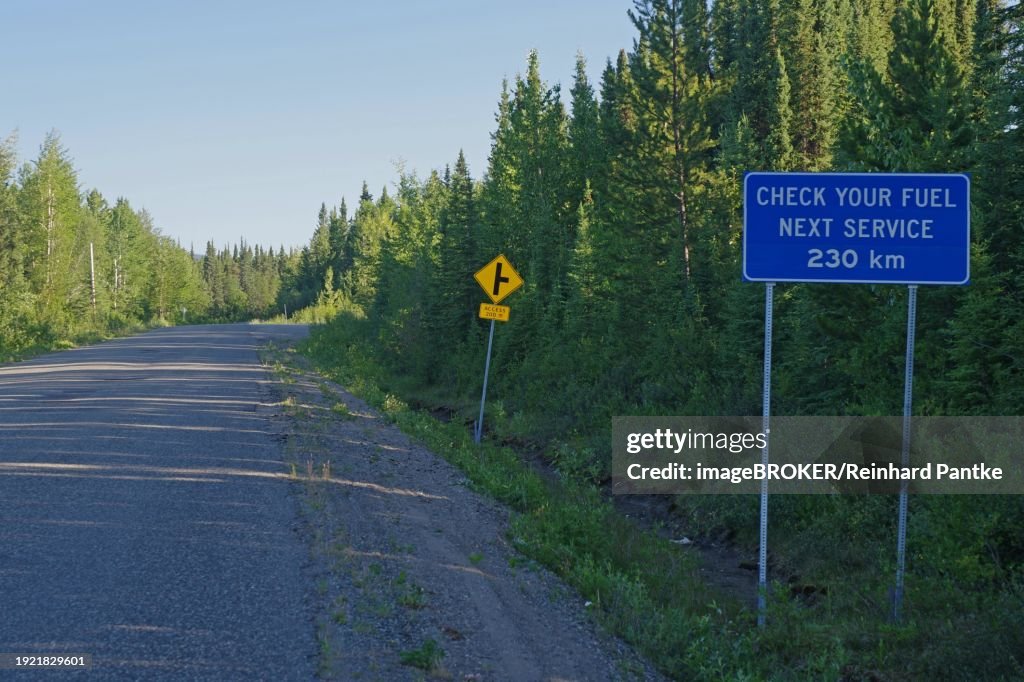 Narrow, traffic-free road and a sign pointing to the next petrol station, mountain landscape, wilderness, Stewart Cassiar Highway, British Columbia, Canada, North America