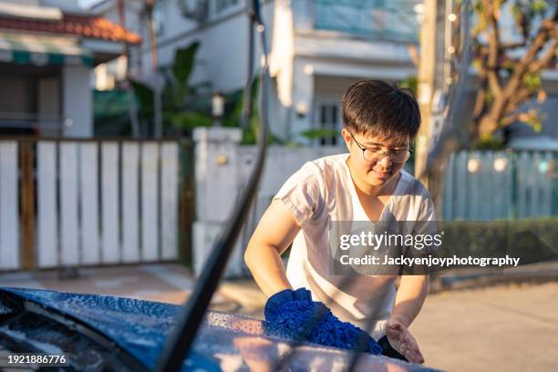 a young man is washing and soap-cleaning his car. - lifehack stock pictures, royalty-free photos & images