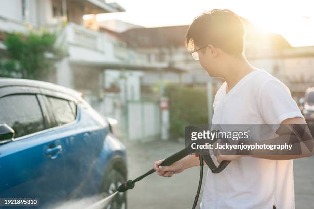 a young asian man using a water sprayer to clean a car - lifehack stock pictures, royalty-free photos & images