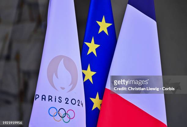 The flag of the Paris 2024 Olympic Games is seen near the French national flag and the European flag at the entrance of the Elysee Palace during the...