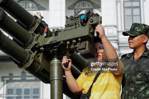 Thai soldier is helping a child aim with a gun on a military tank during National Children's Day inside a military base in Bangkok, Thailand, on...