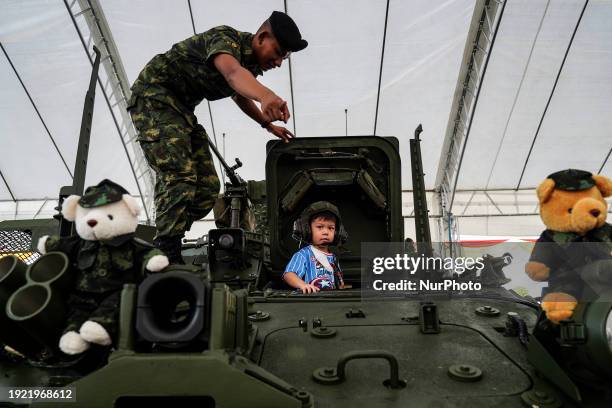 Thai soldier is posing with a child for photos on a military vehicle during National Children's Day inside a military base in Bangkok, Thailand, on...