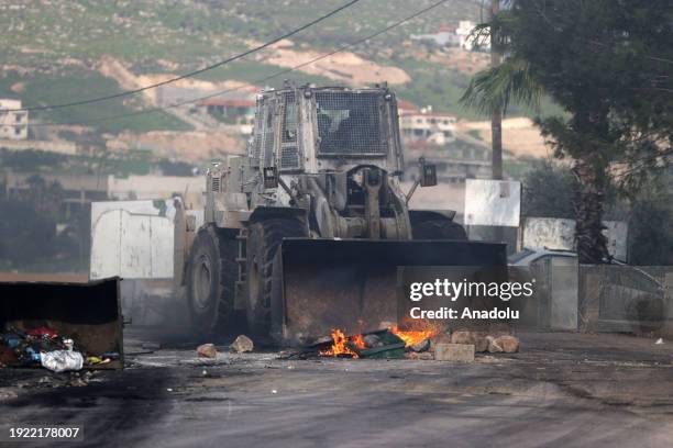 Palestinians burn tires and block roads in response to the Israeli raid on Al-Far'a Refugee Camp, Israeli forces use excavator bucket in an attempt...