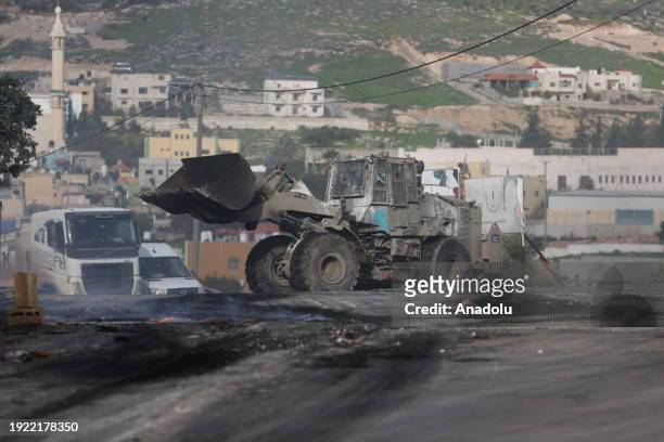 Palestinians burn tires and block roads in response to the Israeli raid on Al-Far'a Refugee Camp, Israeli forces use excavator bucket in an attempt...