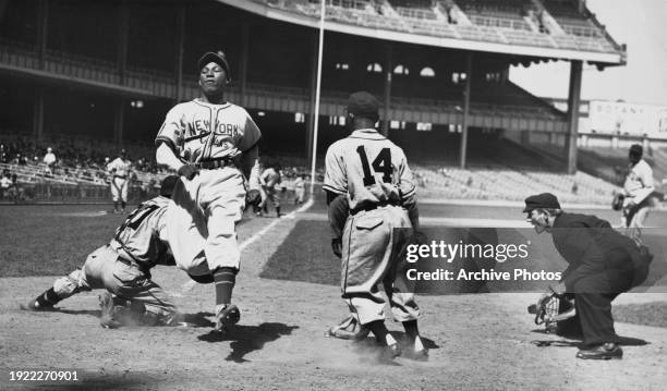 The umpire signals safe as Pedro Ballester from Cuba and Shortstop and Second Baseman for the New York Cubans crosses home plate to score during the...