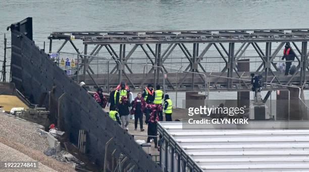 Migrants, some of the first in 2024 to be picked up at sea attempting to cross the English Channel from France, walk to a marquee after disembarking...
