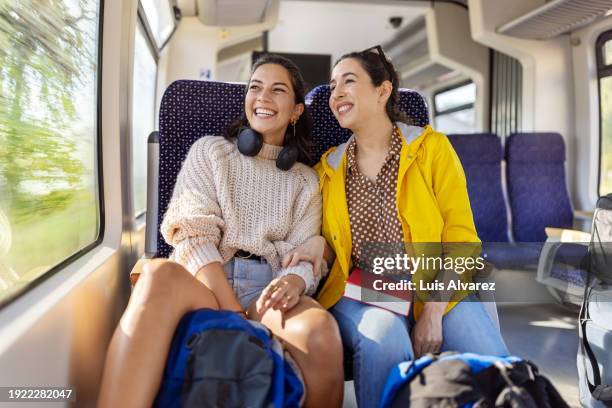 smiling women travelers enjoying a train ride - bahnwaggon innenansicht stock-fotos und bilder