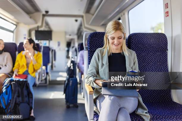young woman using digital tablet while travelling by train - railroad car stock-fotos und bilder