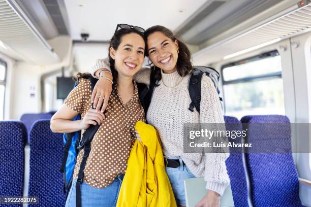 portrait of two women friends standing in train looking at camera and smiling - railroad car stock-fotos und bilder