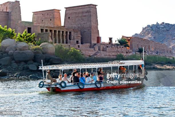 tourist boat approaches temple of philae, aswan, river nile, egypt - aswan stock pictures, royalty-free photos & images