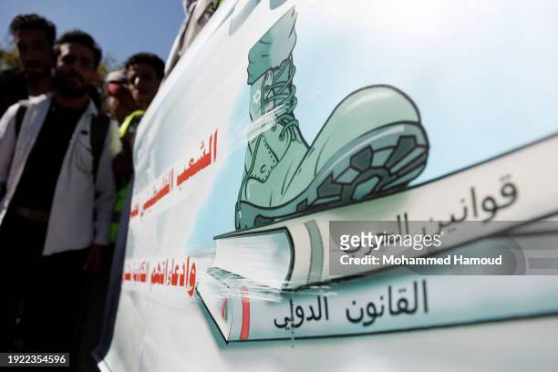 Yemeni university students hold a banner bearing a foot steps books tittled the War Law and International Law that unsee what is happening on Gaza,...