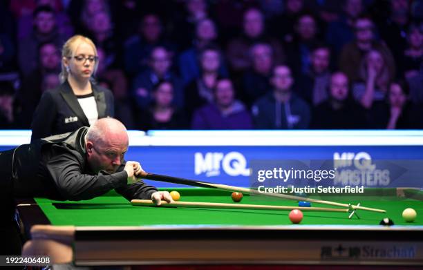 John Higgins of Scotland plays a shot with the rest during his first round match against Mark Allen of England on day four of the MrQ Masters Snooker...