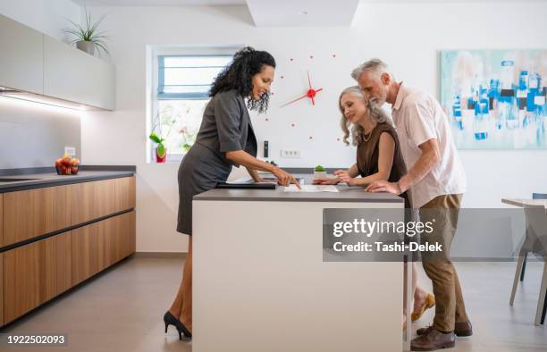 couple and real estate agent checking brochure - high society stock pictures, royalty-free photos & images