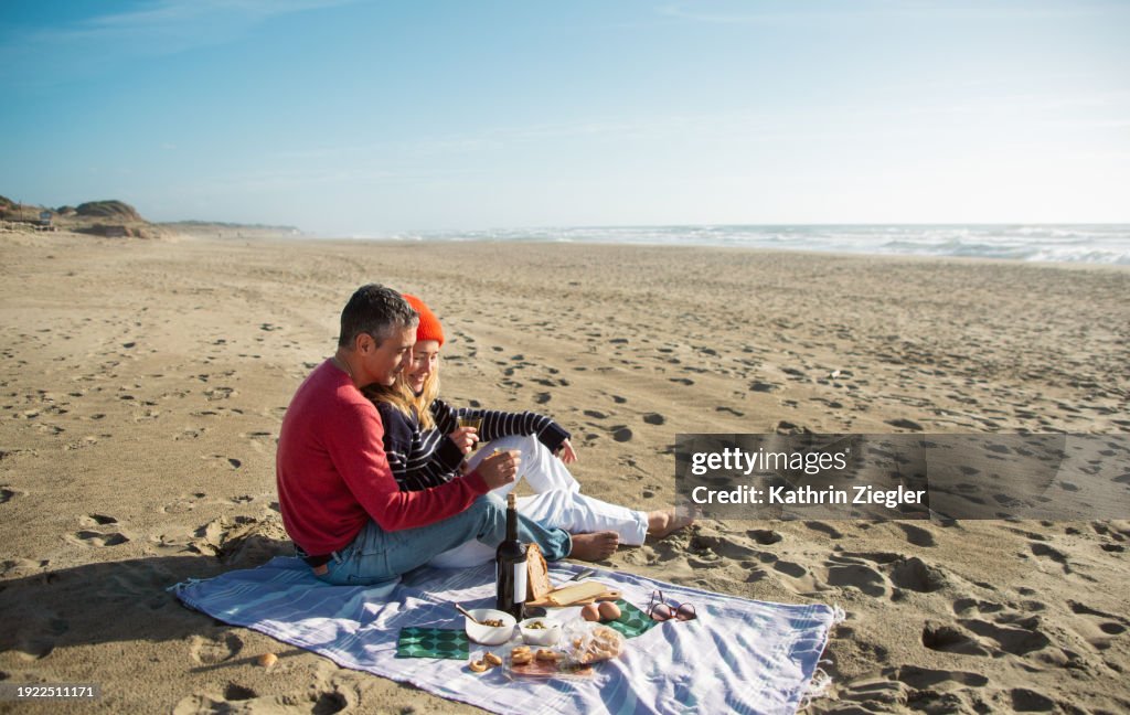 Couple having picnic on the beach on a sunny winter day