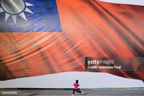 Kid runs across the flag of Taiwan banner during the announcement of official results on January 13, 2024 in Taipei, Taiwan. Taiwan will vote in a...