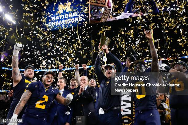 Michigan Wolverines head coach Jim Harbaugh raises the championship trophy after defeating Washington 34-13 during the national championship NCAA...