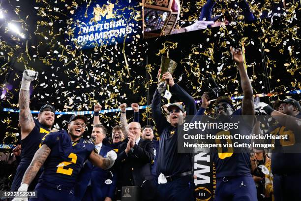 Michigan Wolverines head coach Jim Harbaugh raises the championship trophy after defeating Washington 34-13 during the national championship NCAA...