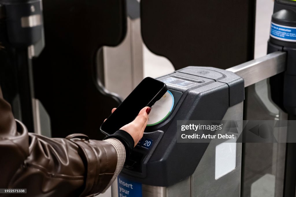 Young girl paying with smartphone contactless wallet in the subway station of London.