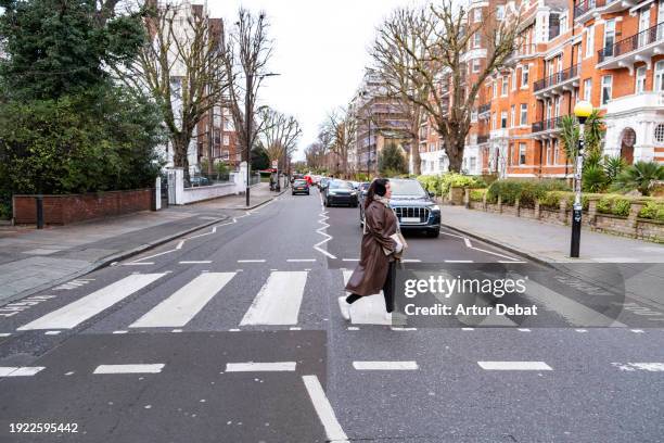 woman crossing the famous abbey road crosswalk in london. - music from the motor city stock pictures, royalty-free photos & images