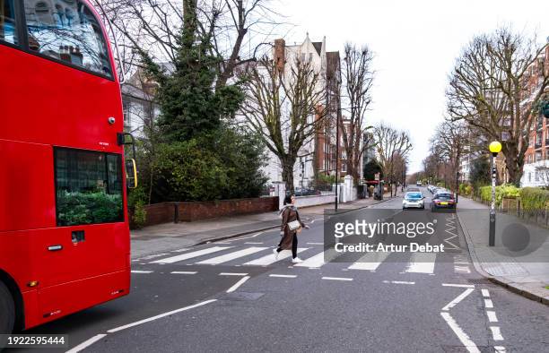 woman crossing the famous abbey road crosswalk in london. - abbey road crossing stock pictures, royalty-free photos & images