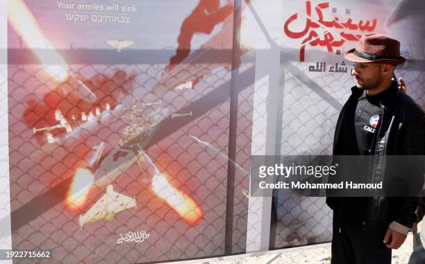 Man looks at a billboard bearing the image of targeting ships, on the day Yemen's Houthi-run forces targeted an American ship in the Red Sea, on a...