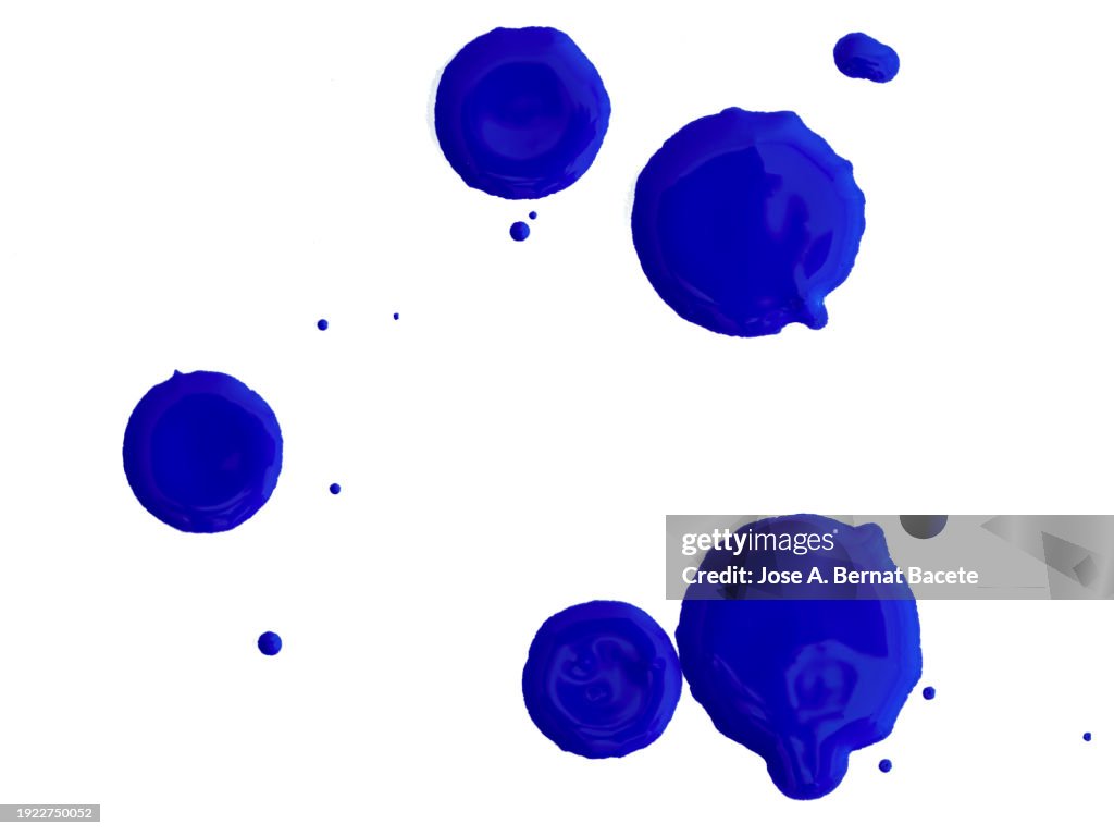 Drops and splashes of blue acrylic paint sliding on a white canvas.
