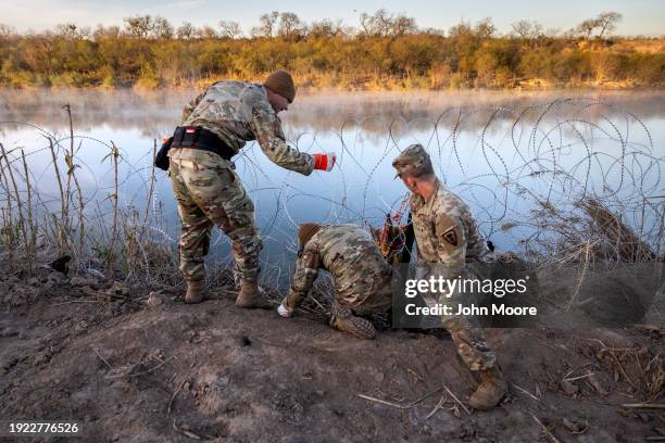 Texas National Guard soldiers install additional razor wire lie along the Rio Grande on January 10, 2024 in Eagle Pass, Texas. Following a major...