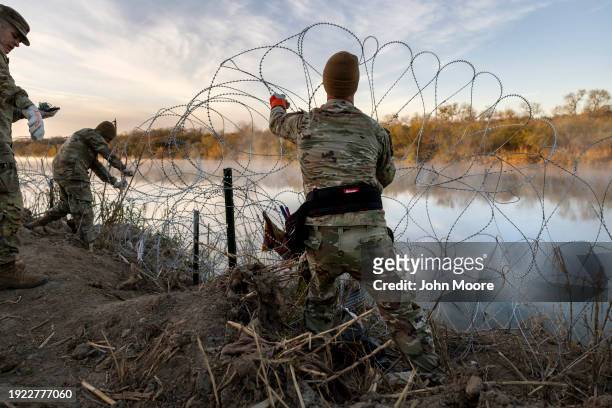 Texas National Guard soldiers install additional razor wire lie along the Rio Grande on January 10, 2024 in Eagle Pass, Texas. Following a major...