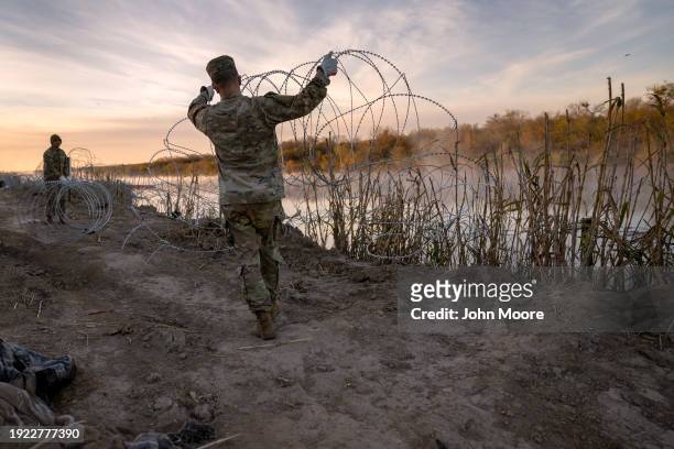 Texas National Guard soldiers install additional razor wire lie along the Rio Grande on January 10, 2024 in Eagle Pass, Texas. Following a major...