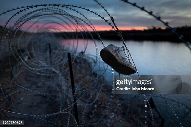 Child's shoe hangs caught in razor wire atop the bank of the Rio Grande on January 9, 2024 in Eagle Pass, Texas. Following a major surge of migrant...