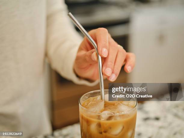 woman putting resuable metal straw in an iced coffee drink - iced coffee stock pictures, royalty-free photos & images