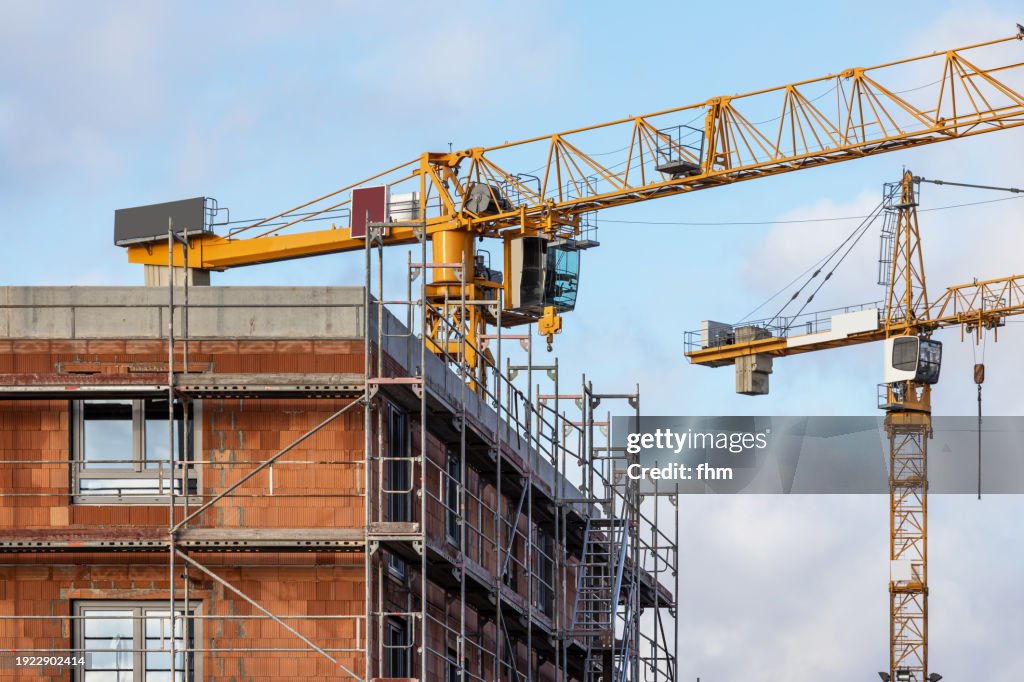 Construction site of a residential building with scaffolding and large cranes