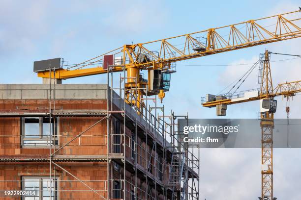 construction site of a residential building with scaffolding and large cranes - fazer imagens e fotografias de stock