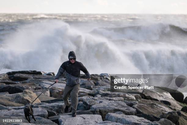 Man walks with his dog along the beach at Rockaway during heavy surf following a storm that brought high winds and rain to the area on January 10,...