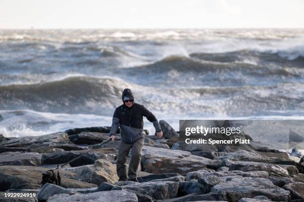 Man walks with his dog along the beach at Rockaway during heavy surf following a storm that brought high winds and rain to the area on January 10,...