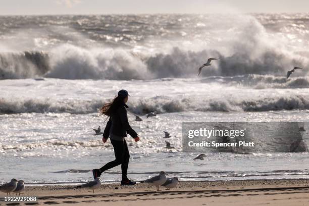 Woman walks along the beach at Rockaway during heavy surf following a storm that brought high winds and rain to the area on January 10, 2024 in New...