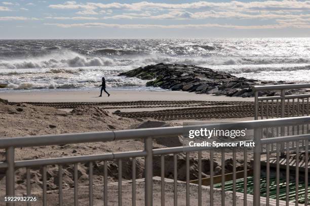 People walk along the beach at Rockaway during heavy surf following a storm that brought high winds and rain to the area on January 10, 2024 in New...