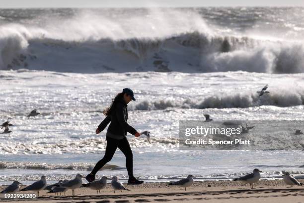 Woman walks along the beach at Rockaway during heavy surf following a storm that brought high winds and rain to the area on January 10, 2024 in New...