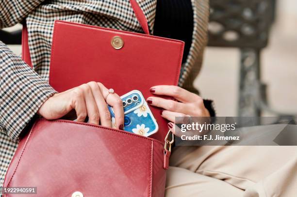 close-up of woman's hands taking out mobile phone from bag - handtasche stock-fotos und bilder