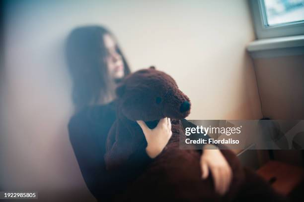 teenage girl hugging a large teddy toy bear. problems of puberty, loneliness and misunderstanding in the family with parents. selective focus - abused girl stock pictures, royalty-free photos & images