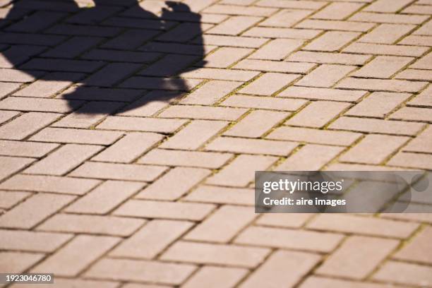 a floor with rustic cement tiles, in a rectangular geometric shape, placed in different positions, illuminated by sunlight with a shadow of a silhouette of a person. - amsterdam street stock pictures, royalty-free photos & images