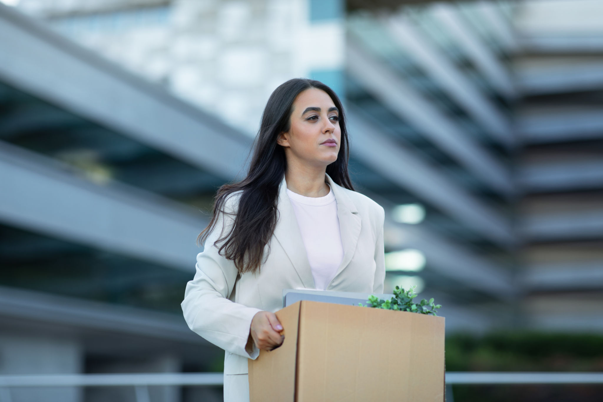 Sad business lady carrying box belongings leaving office after layoff Sad business lady carrying box belongings leaving office after layoff
