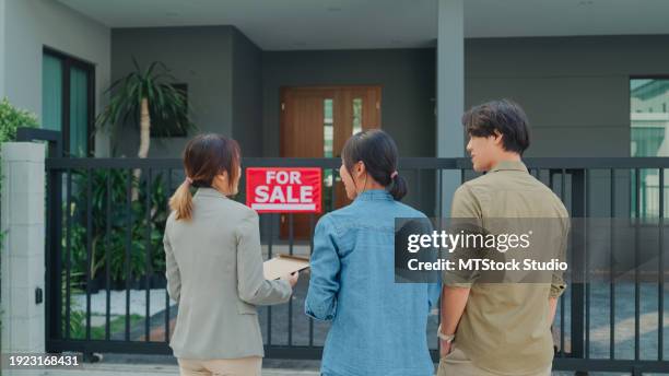 young asian woman real estate broker showing house to client buyers outside at home. buying a new house. - visita de inmuebles en venta fotografías e imágenes de stock