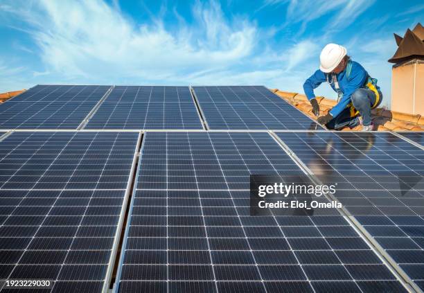 professional female worker installing solar panels on the roof of a house - solpanel bildbanksfoton och bilder